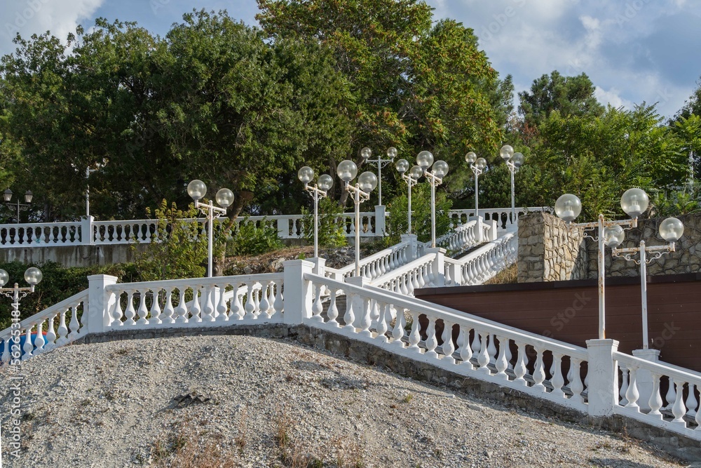 Gelendzhik bay. Embankment of resort town. Large staircase with stone balusters with lanterns from embankment to city beach. Selective focus. Atmosphere of serene rest and relaxation.