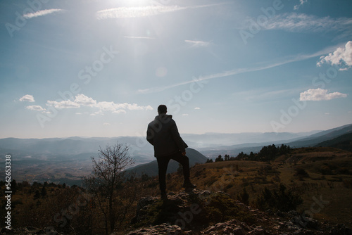 Hiking concept. Man having trekking in the mountains. Hiker on the rocks at sunny day in autumn. 