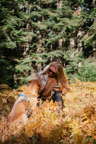 Woman having fun with a dog in the forest. Having trekking with pets concept. Walking in the forest in autumn. 