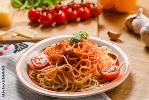 Pasta with tomatoes on the background of parmesan cheese, garlic, herbs and cherry tomatoes.