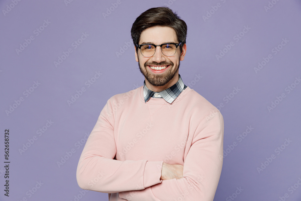 Young smiling fun happy smart cheerful caucasian IT man wear casual clothes pink sweater glasses hold hands crossed folded look camera isolated on plain pastel light purple background studio portrait. Young smiling fun happy smart cheerful caucasian IT man wear casual clothes pink sweater glasses hold hands crossed folded look camera isolated on plain pastel light purple background studio portrait.