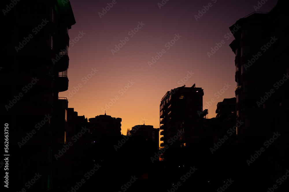 City houses in sunset, silhouettes of houses against dark purple sunset sky