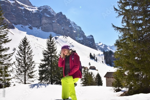 young woman covers her face with her hands from the sun in the snowy mountains photo