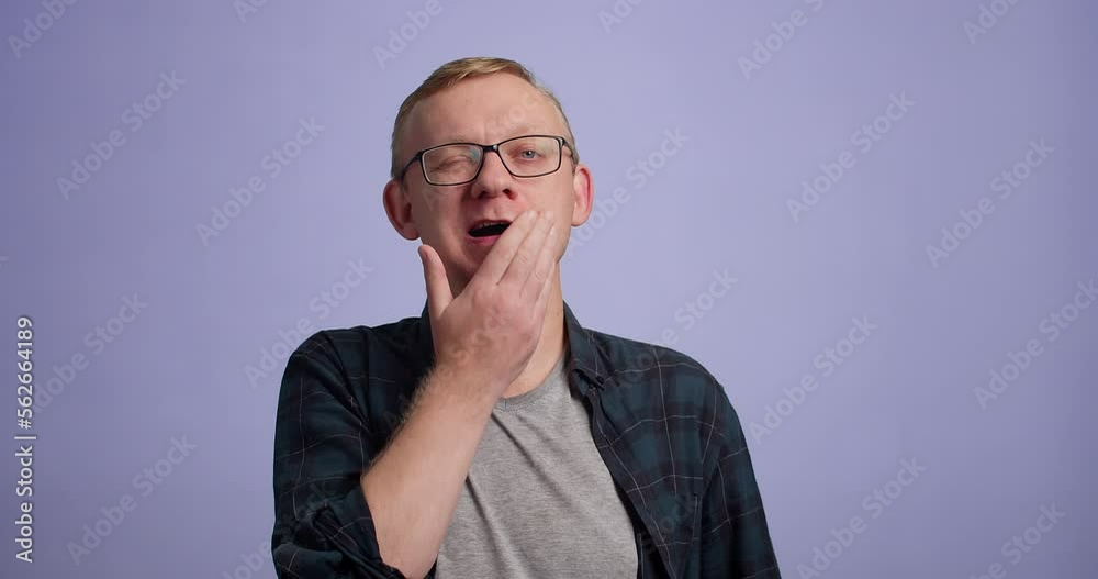 Man looking camera yawning want to sleep cover mouth with hand, studio shot