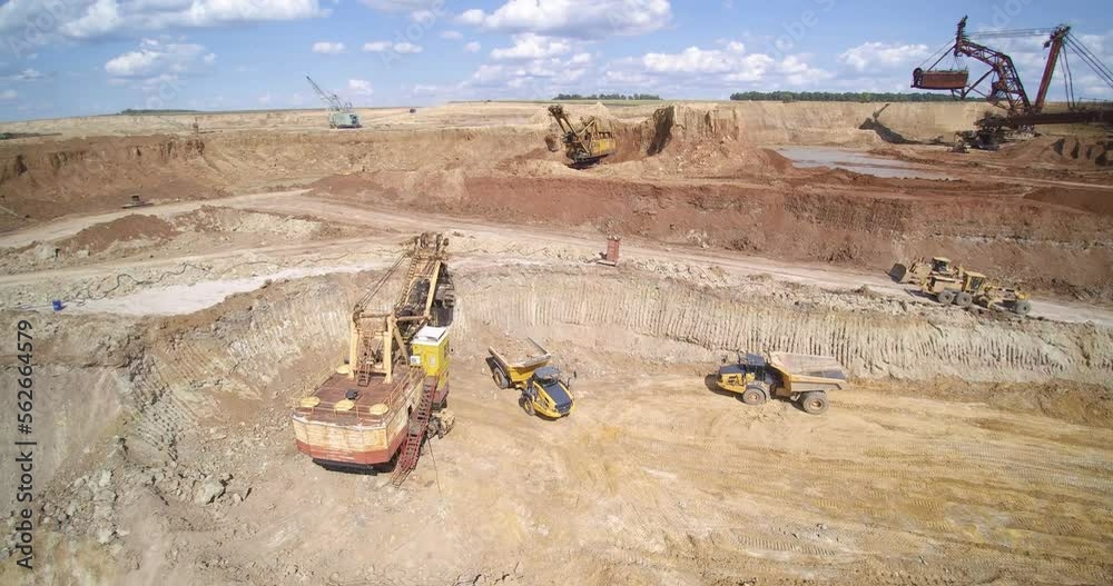 backhoe loader puts sand into quarry dump truck against working bucket wheel excavator and technics aerial view
