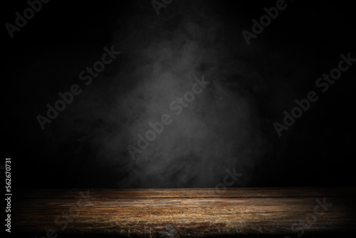Dark empty wooden table with smoke float up on dark wall background. Free space for your decoration. 