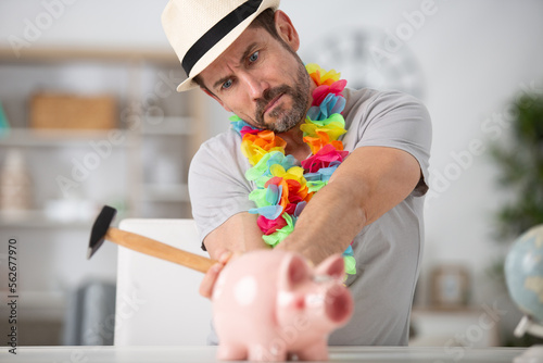 serious man breaking piggy bank with hammer photo