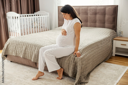 A pregnant woman is having labor pain in a bedroom.