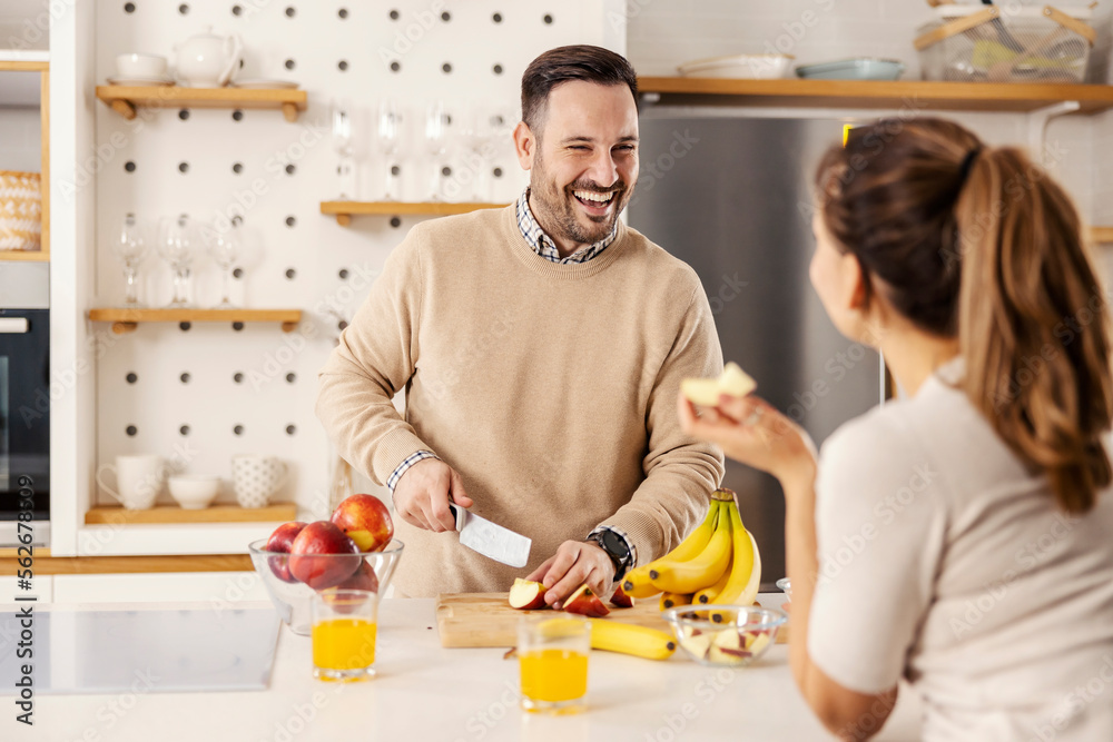 A happy man is cutting apples in kitchen and preparing healthy snack for him and his wife. A happy man is cutting apples in kitchen and preparing healthy snack for him and his wife.