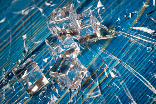 Ice cubes with water drops on a blue wooden surface.