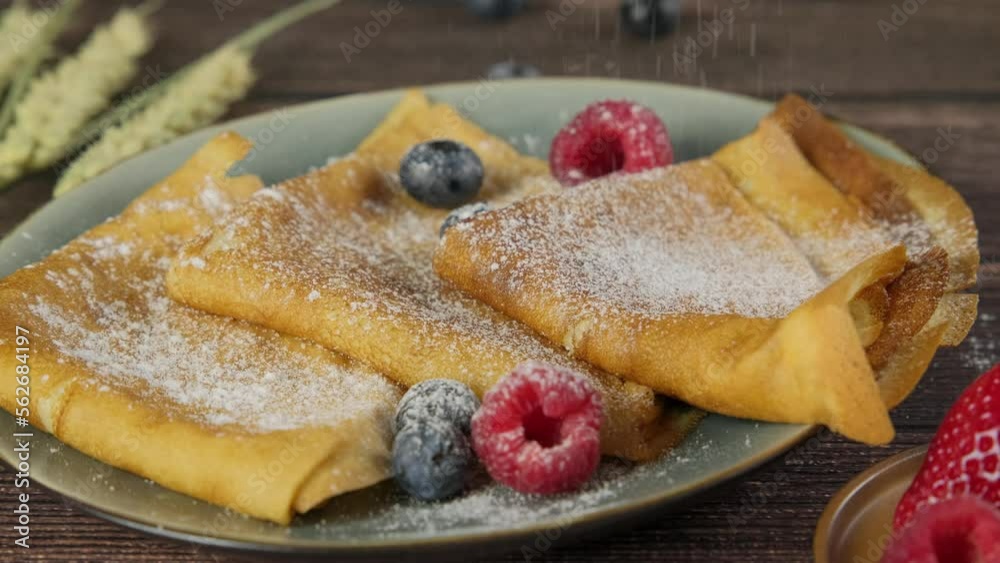 French crepes being sprinkled with sugar powder, thin pancakes folded and served on plate with fresh berries, delicious Russian pancakes, high quality slow motion video clip, 4k footage French crepes being sprinkled with sugar powder, thin pancakes folded and served on plate with fresh berries, delicious Russian pancakes, high quality slow motion video clip, 4k footage