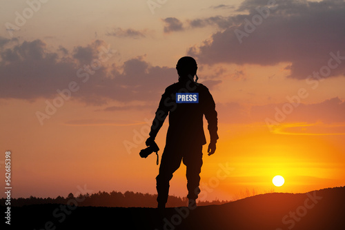 Photojournalist silhouette documenting war or conflict. Photojournalist at sunset. War, army, technology and journalist work concept.