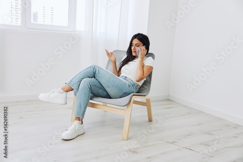 A woman talking on the phone at home sitting in a chair and smiling with her teeth, online communication as a lifestyle