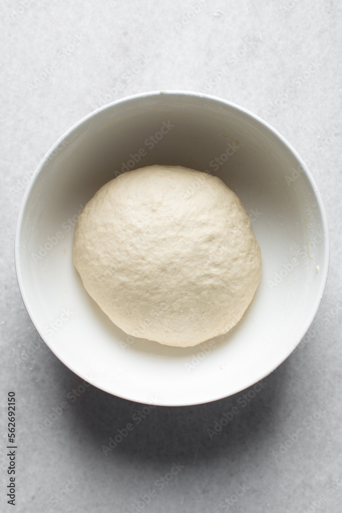 Bread dough resting in a bowl, dough that is rising,  proofing dough in a white bowl