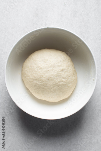 Bread dough resting in a bowl, dough that is rising, proofing dough in a white bowl