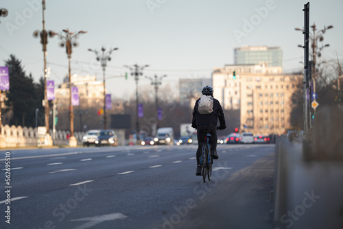 Going to work by bike. Photo with a biker from behind commuting to work on a bike in the middle of a city. Eco friendly transportation concept image. © Dragoș Asaftei