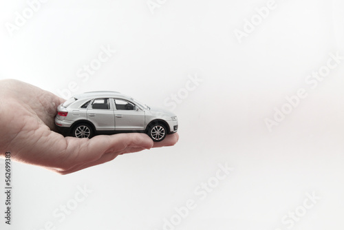 Image of a miniature car held by a hand on white background with copy space