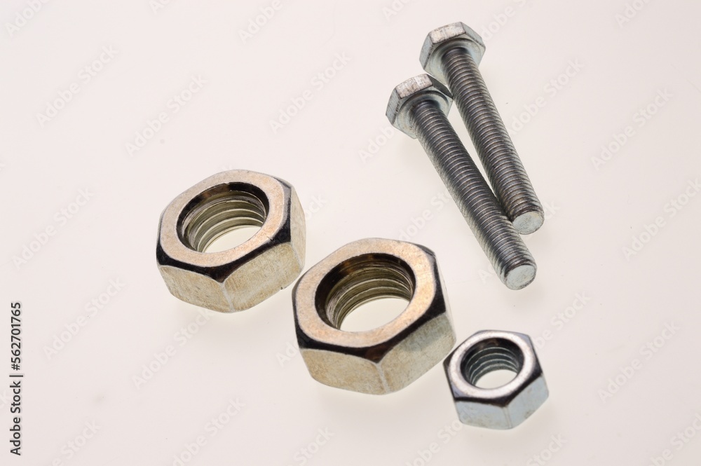 New, chrome-plated bolts and nuts of different sizes lie on a white background. Close-up New, chrome-plated bolts and nuts of different sizes lie on a white background. Close-up