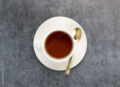Cup of black hot tea with a spoon on a green background. Top view.