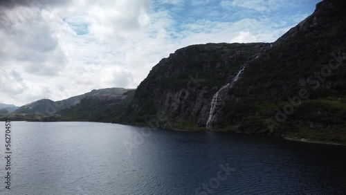 Slide over a lake in the mountains of norway with a waterfall