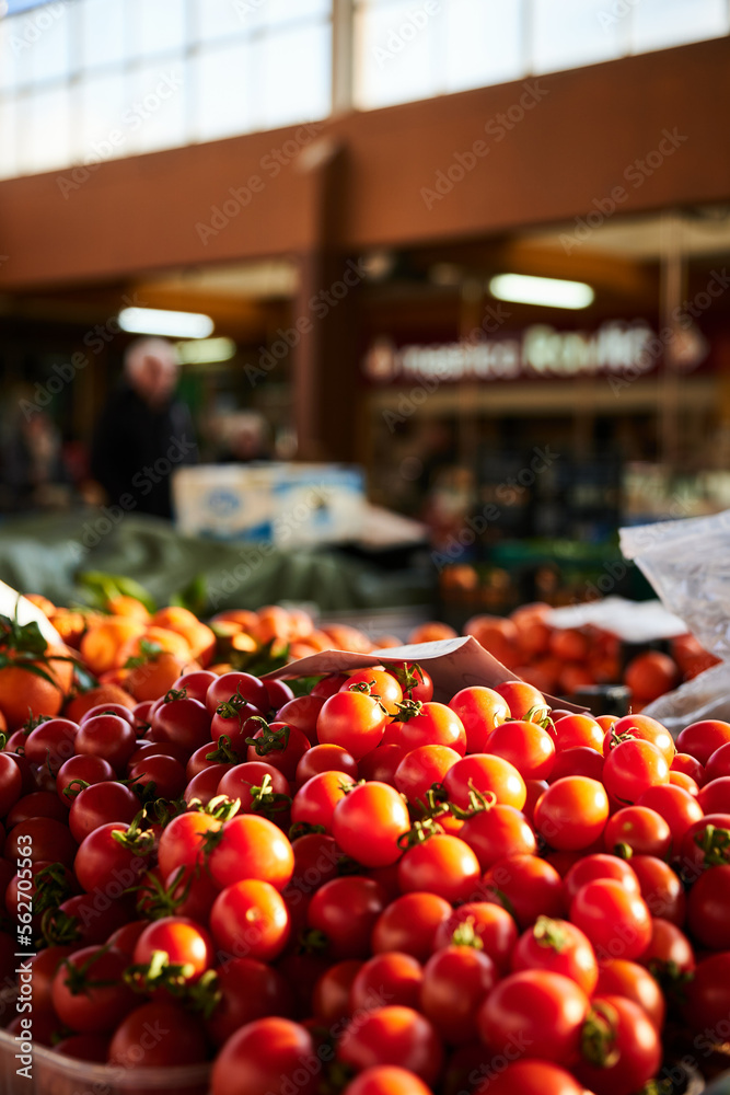 Fresh red tomatoes in close up, on a market stall, inside of a farmers market in the background.
