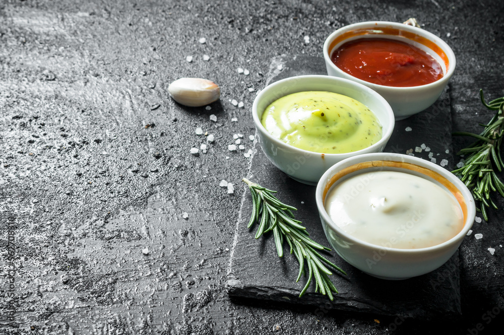 Delicious sauces guacomole, mayonnaise and ketchup with cloves of garlic and rosemary.