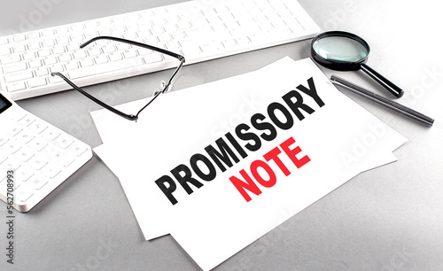 PROMISSORY NOTE text on a paper with keyboard, calculator on grey background photo