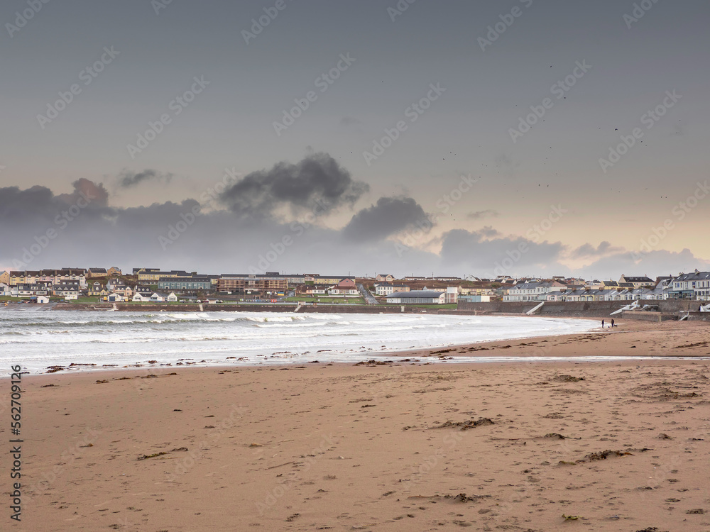 View on Kilkee beach and town houses in the background. County Clare, Ireland. Nobody. Popular summer resort. Atlantic ocean, Irish seascape. Cloudy sky.