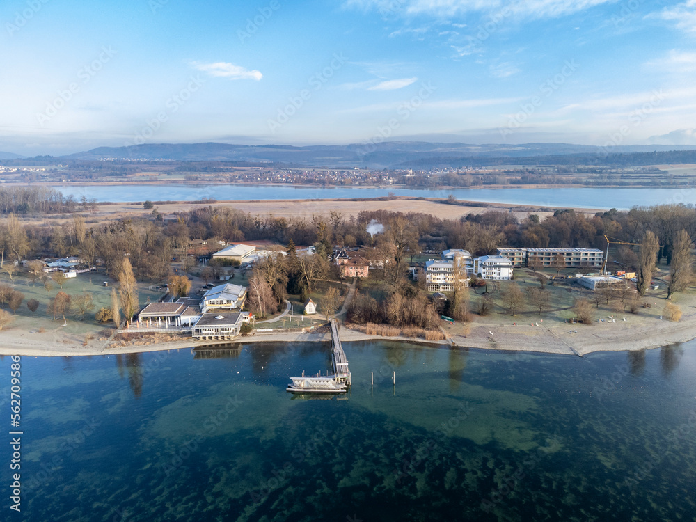 Luftaufnahme von der Halbinsel Mettnau mit dem Schiffanleger, Strandcafe und Kur- und Rehazentrum, am Horizont die Ortschaft Markelfingen