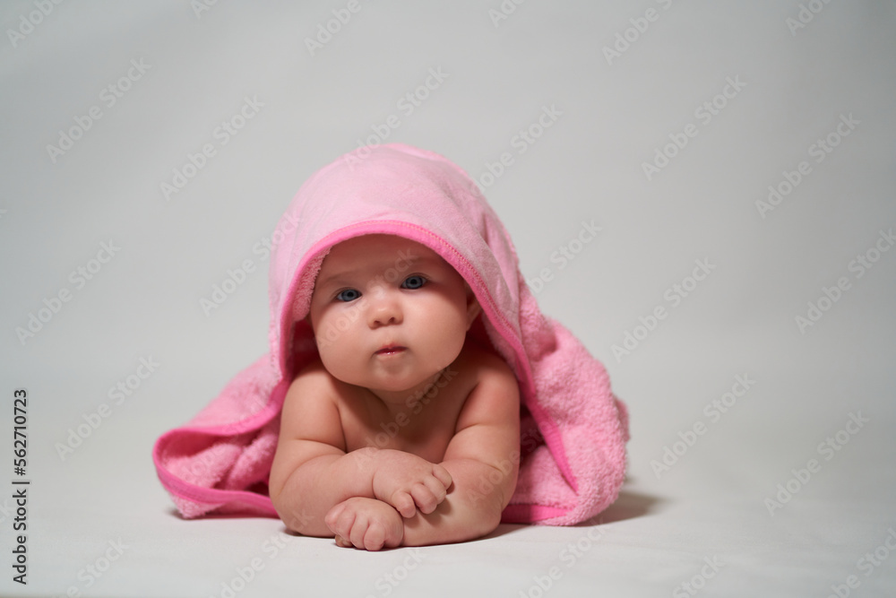 Portrait of a baby on a light background with a pink towel Portrait of a baby on a light background with a pink towel