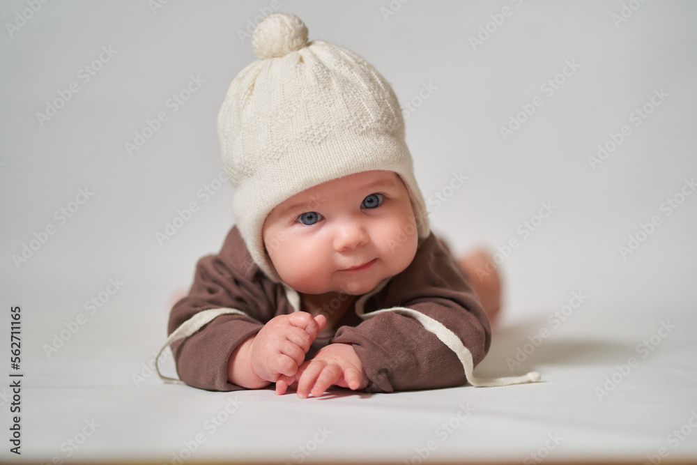 portrait of an infant on a light background in a warm knitted white hat portrait of an infant on a light background in a warm knitted white hat