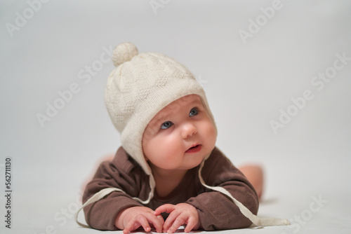 portrait of a keen infant on a light background in a warm knitted white hat