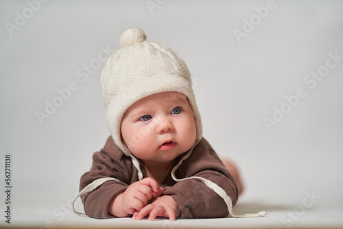 portrait of an infant on a light background in a warm knitted white hat