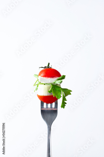 close-up of a pomelo cherry feta cheese sprig of parsley stabbed on a fork on a white background
