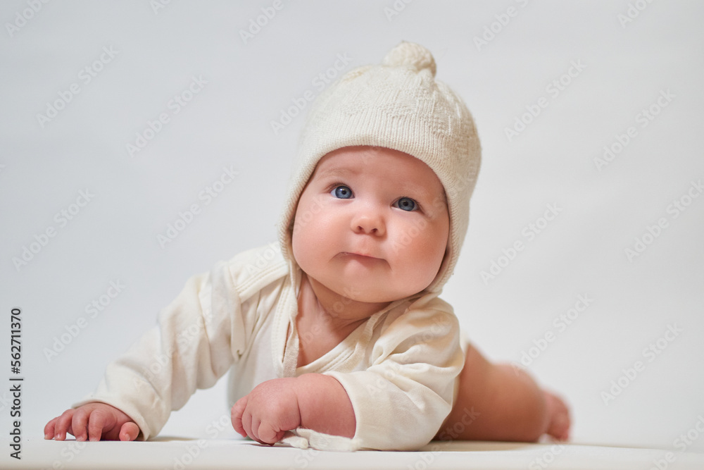 Portrait of an infant in light clothing and a knitted hat on a white background Portrait of an infant in light clothing and a knitted hat on a white background