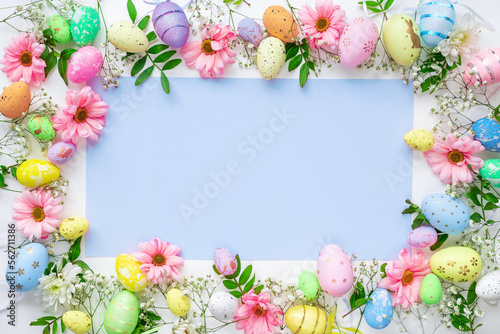 Fototapeta Naklejka Na Ścianę i Meble -  Colorful eggs with flowers on a white and blue background. Easter design in pastel colors with space for text. Holiday template, top view.