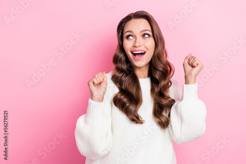 Portrait of glad pretty girl raise fists look empty space success shout yes isolated on pink color background
