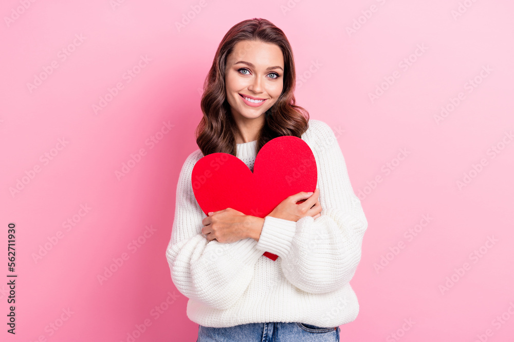 Portrait of good mood fancy girl with curly hairstyle wear knit pullover hold embrace red paper heart isolated on pink color background Portrait of good mood fancy girl with curly hairstyle wear knit pullover hold embrace red paper heart isolated on pink color background