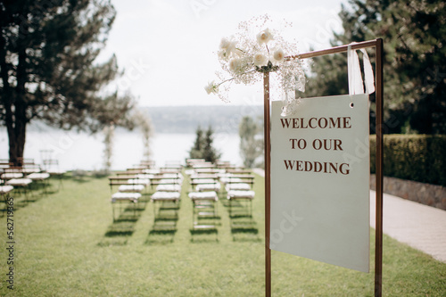 wedding reception board on the background of the decorated ceremony, empty rows of chairs, preparation for the wedding ceremony, waiting for guests