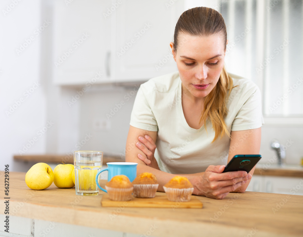 Portrait of woman using smartphone in kitchen at home Portrait of woman using smartphone in kitchen at home