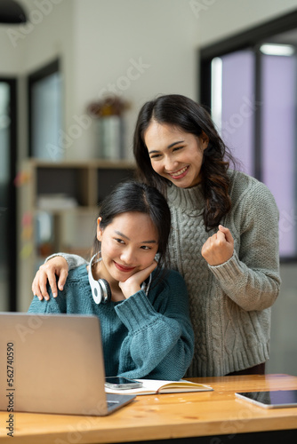 Two young Asian businesswomen discuss with smiles and joy financial management planning. New startup project ideas, and financial and statistical analysis seamlessly.