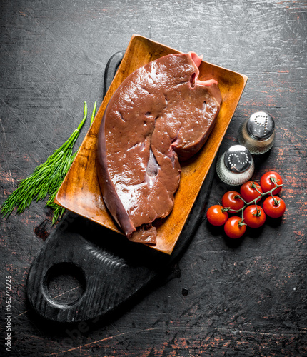 Raw liver with herbs, tomatoes and spices on the cutting Board. photo