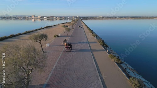 Wallpaper Mural Aerial tracking video of friends riding tricycle bike buddy on a embankment promenade surrounded by the calm sea water with a San Pedro Del Pinatar touristic city in a background. Costa Blanca region  Torontodigital.ca