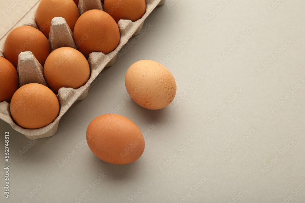 Chicken eggs in an open egg carton on grey. Top view with copy space. Natural healthy food and organic farming concept. Chicken eggs in an open egg carton on grey. Top view with copy space. Natural healthy food and organic farming concept.