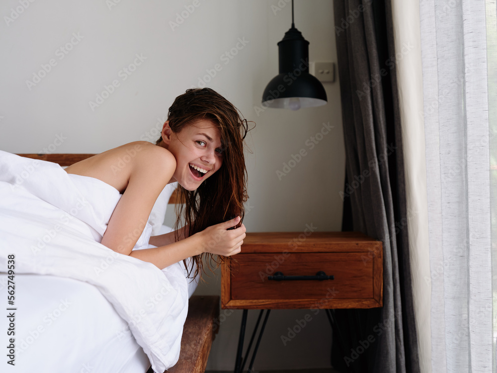 A woman after a shower lies on a bed in a bedroom near a window with wet hair, a healthy sleep on an orthopedic patras and a pillow with a memory effect A woman after a shower lies on a bed in a bedroom near a window with wet hair, a healthy sleep on an orthopedic patras and a pillow with a memory effect