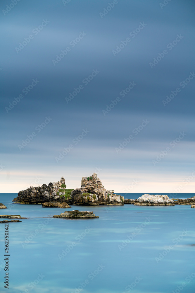 View of rocks on sea after sunset time with beautiful blue sea water and cloudy sky, long exposure photography on outdoor
