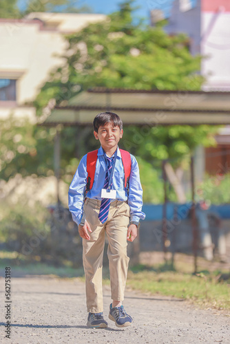 An Indian or asian little boy running on the road. Coming or going to school from home. Smiling kid.