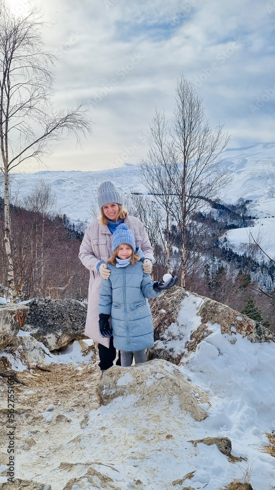 mother and daughter against the backdrop of a winter mountain landscape. the concept of winter trips and hikes with children.