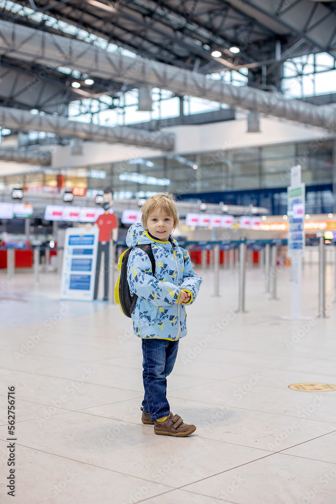 Cute  baby boy waiting boarding to flight in airport transit hall near departure gate. Active family lifestyle travel by air with children