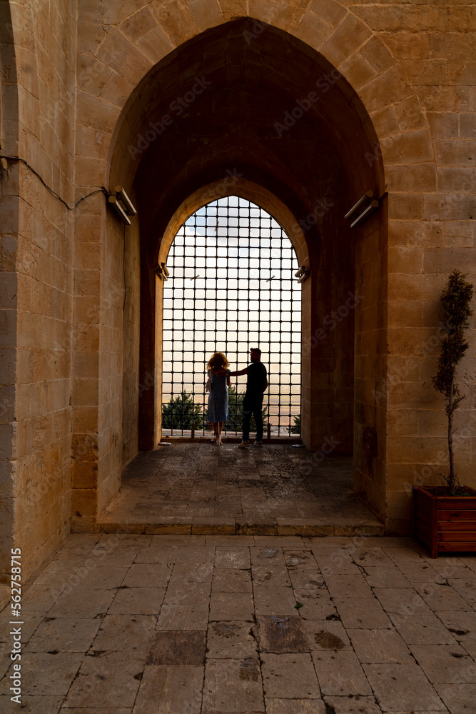 Inside viev of Kasimiye Madrasah of Mardin Province, beautiful stone architecture religion school with colorful sunset light and fences and people